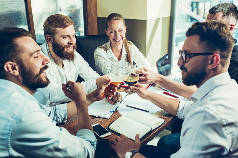 5 professionnels se réunissent autour d'une table chargée de documents et d'un PC pour finaliser les détails de leur partenariat. Ils élaborent un contrat solide qui renforce leurs liens et leur engagement mutuel dans le réseau. C'est un exemple concret de collaboration efficace et de travail d'équipe pour atteindre des objectifs communs.