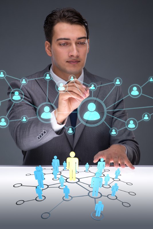 Un homme utilise la technologie holographique pour sélectionner les profils idéaux au sein de son réseau. Sa concentration et son engagement témoignent de l'importance stratégique de cette décision pour renforcer son réseau professionnel.